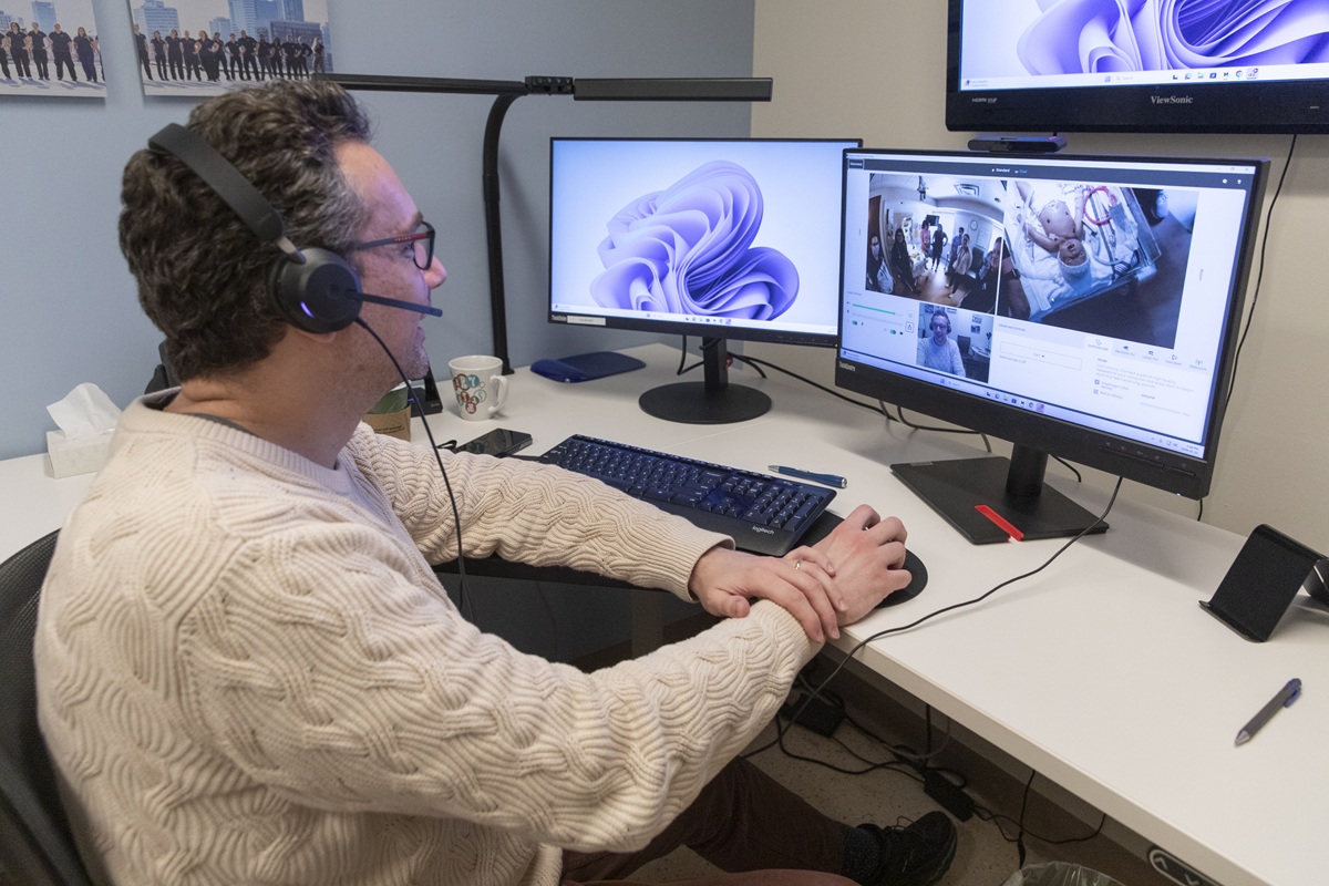 SickKids staff member wearing a headset looks at a screen with a baby mannequin during simulation session.