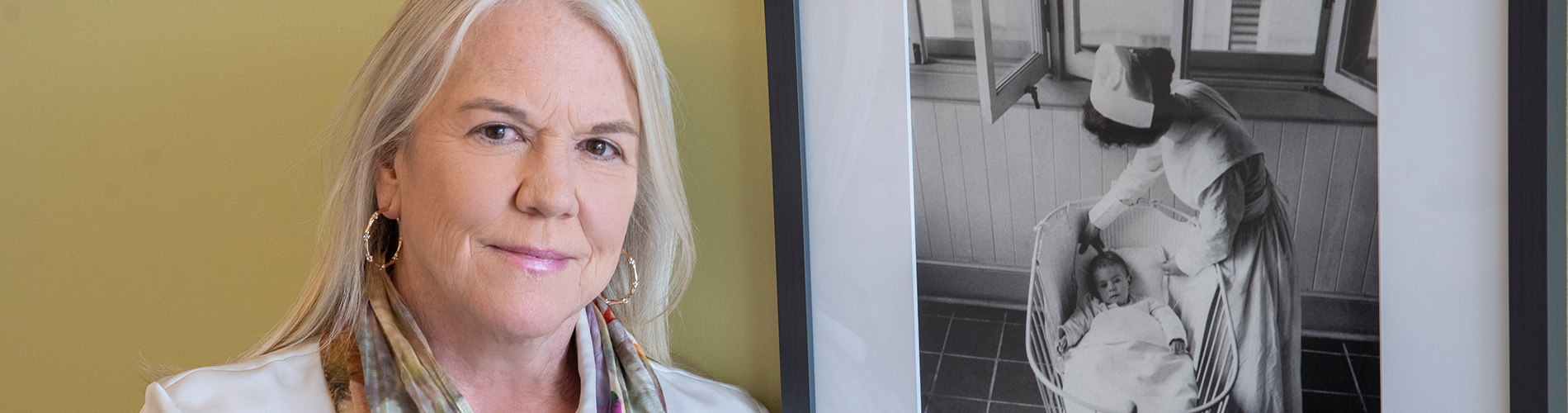 Dr. Jennifer Stinson stands beside a photo of a SickKids nurse from c. 1915