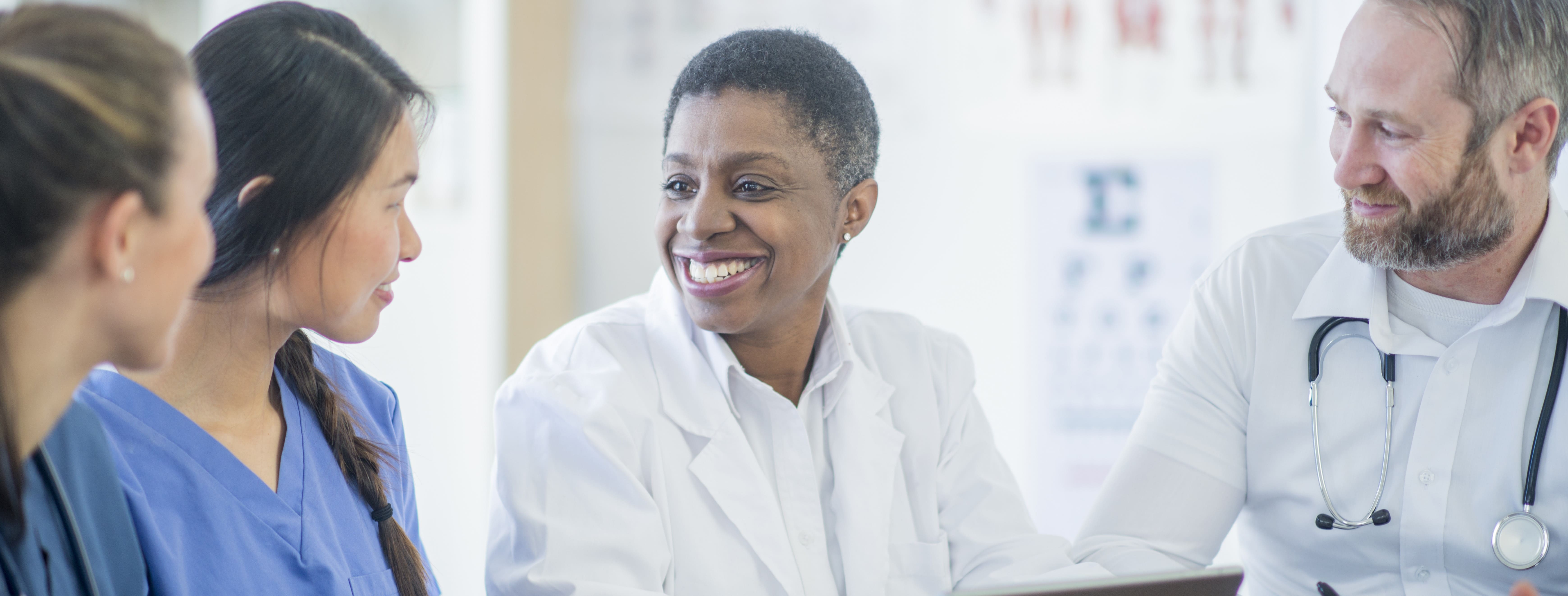 4 smiling medical colleagues sitting at a table with papers