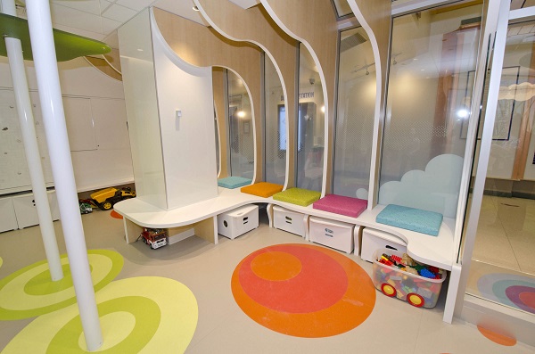 Play area showing bins of toys and a bench seat with colourful circles on the floor.