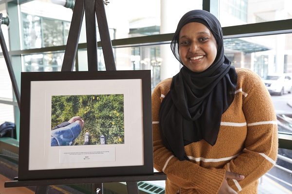 Smiling teen stands next to framed image on an easel.