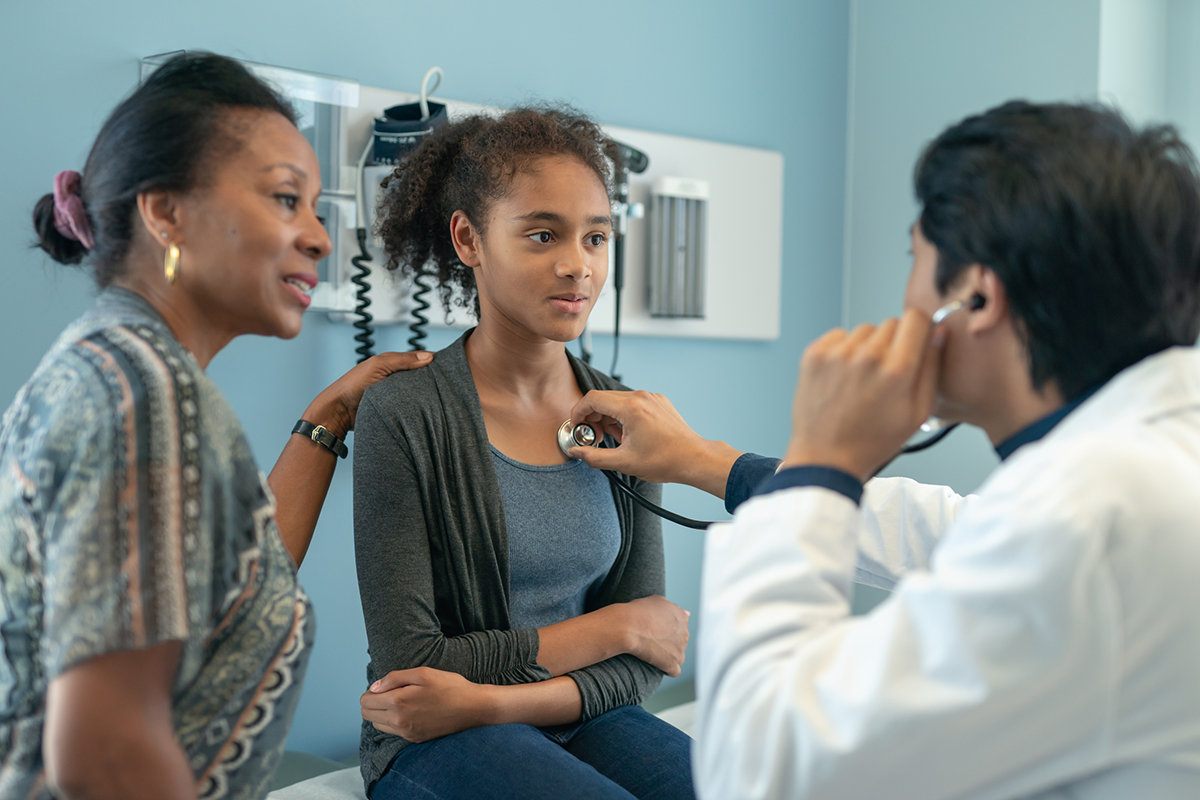 A doctor listens to a young girl's breathing.