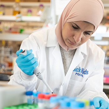 A woman wearing a lab coat conducts research at the bench.