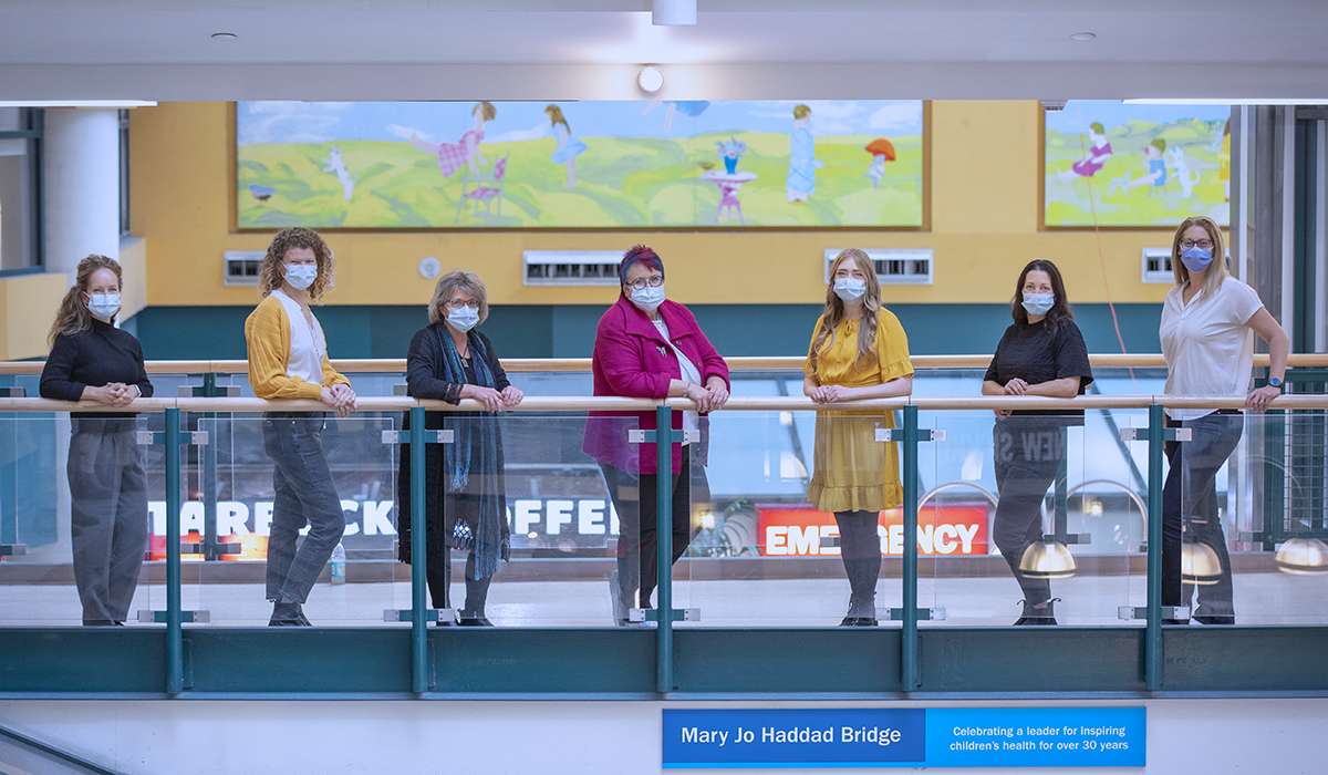 Seven people standing in masks on the Mary Jo Haddad Bridge in the Atrium.