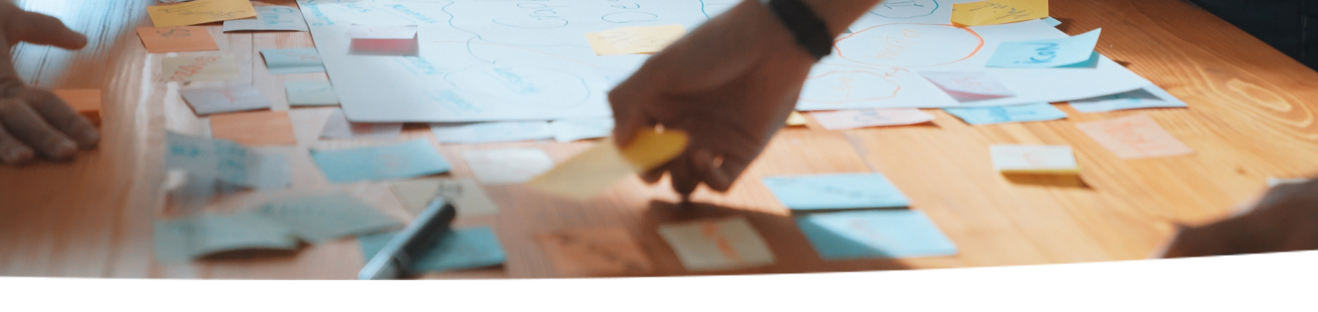 Hands placing sticky notes on a table.