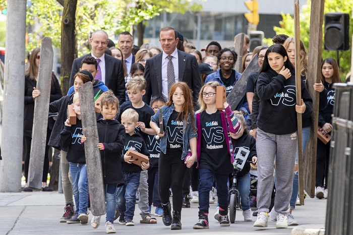 Peter Gilgan, Ronald Cohn and SickKids patients walk together on a street