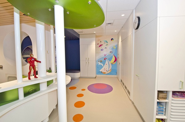 A beach scene on a wall at the end of a hallway with cupboards on one side and pillars on the left.