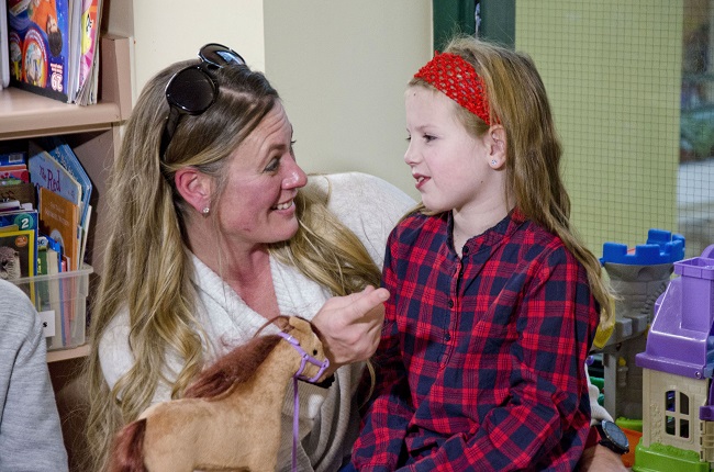 Girl sits on her mother's lap.