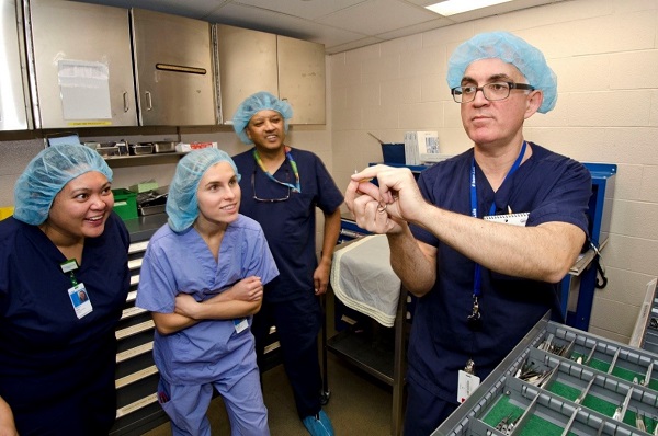 Lab manager holds a small device. Three other staff look at it closely.