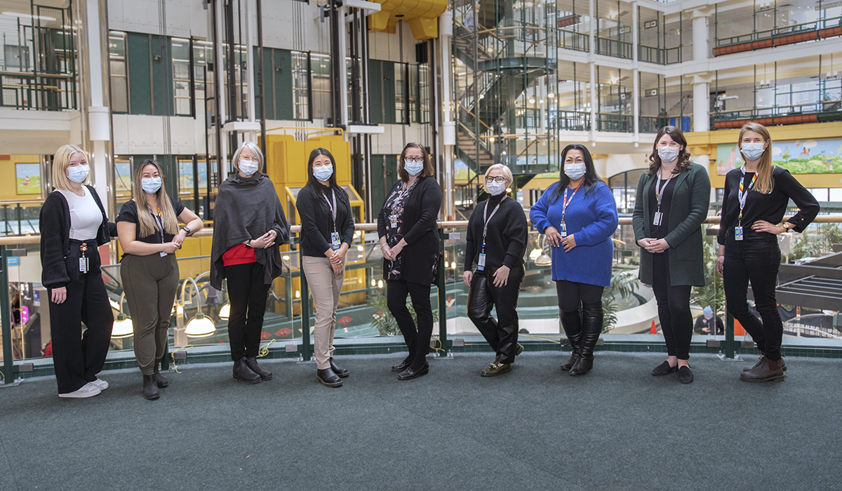 A group of people in masks standing in the Atrium.