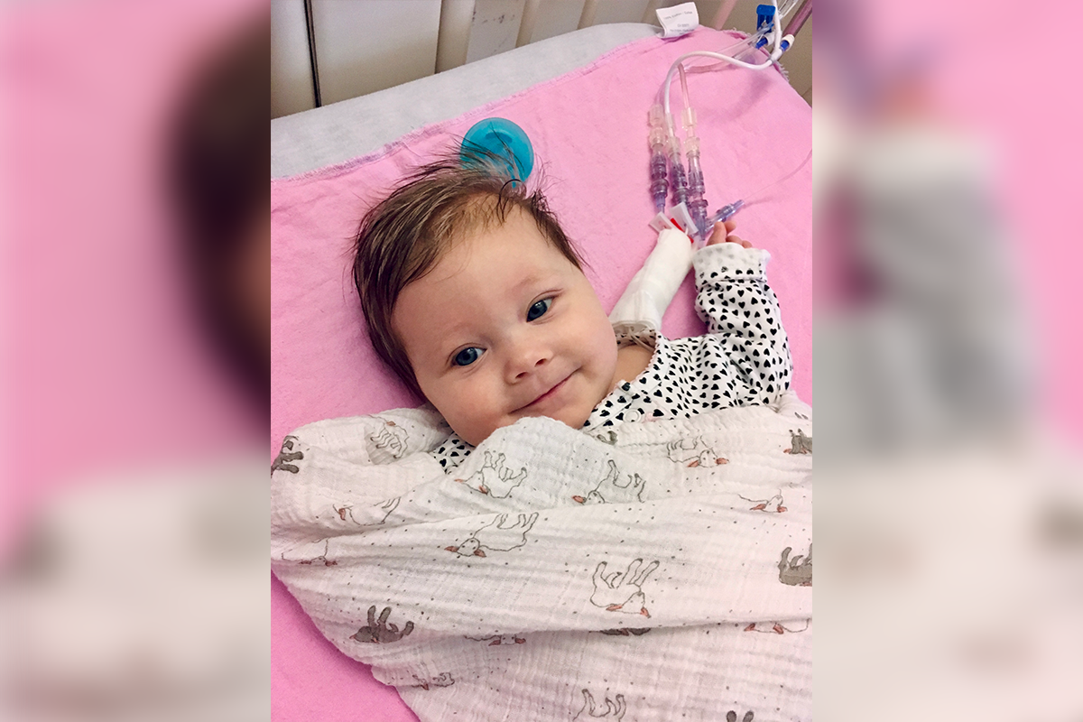 A baby on a hospital bed with tubes attached to their stomach.