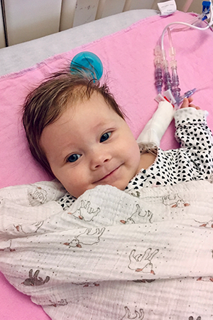 A baby on a hospital bed with tubes attached to their stomach.