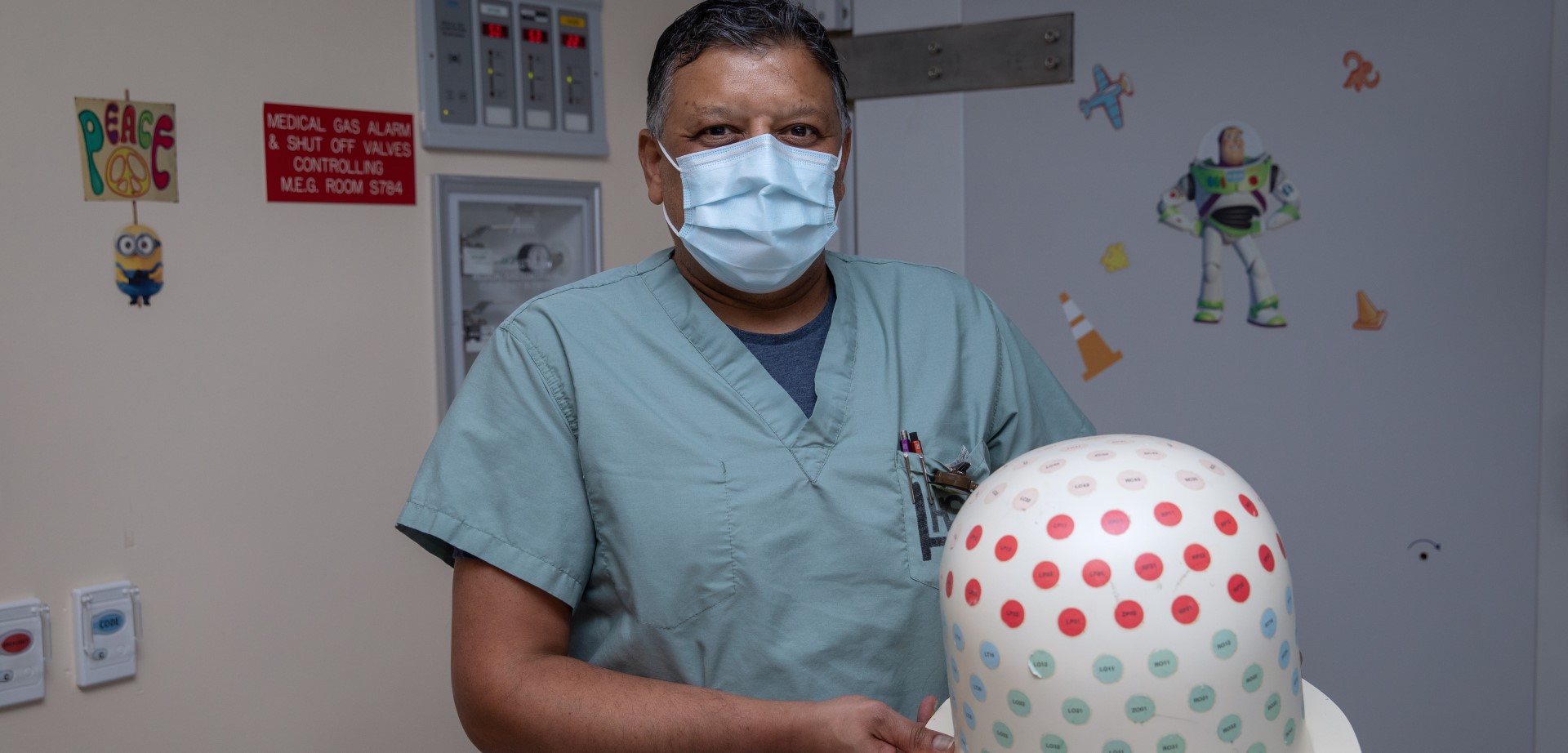 Roy Sharma in a mask holding a piece of equipment.