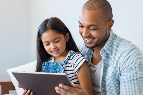 Adult and child use a tablet together.