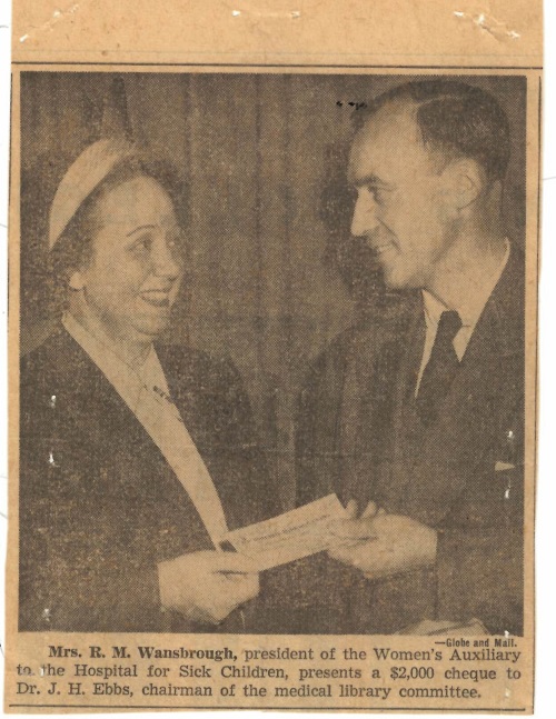 Scan of a photo in an old newspaper. A woman hands a cheque to a man.