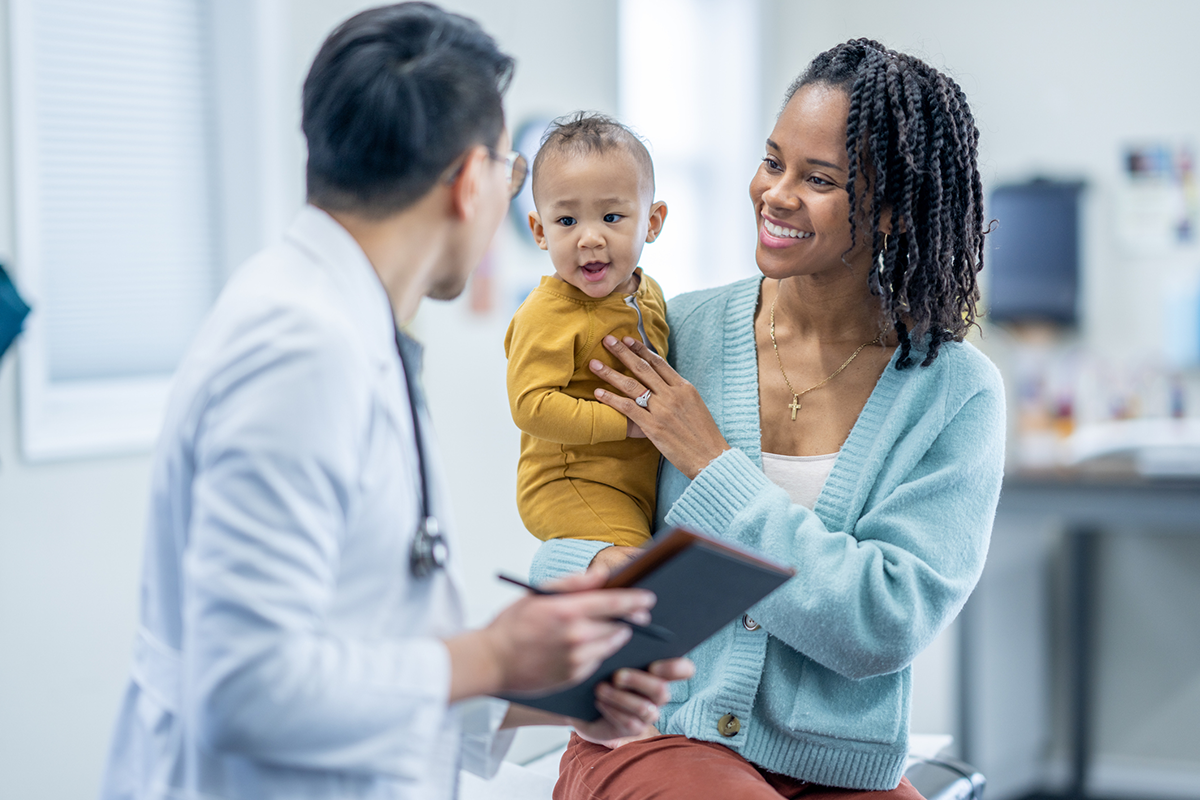 A women holding a child talks to a doctor.