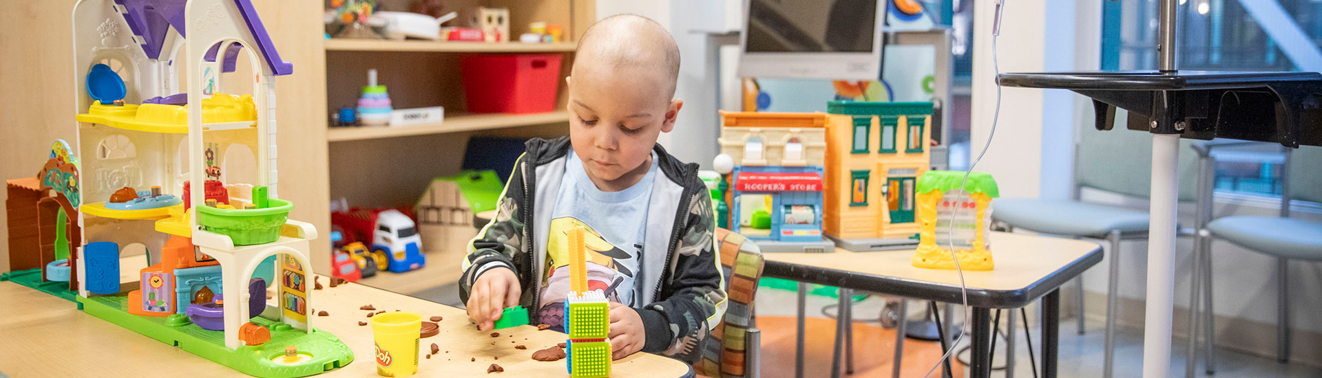 A young boy plays with clay in a waiting room at SickKids.