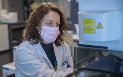 Emily Reddy in a mask and interacting with an instrument at the Flow Facility.