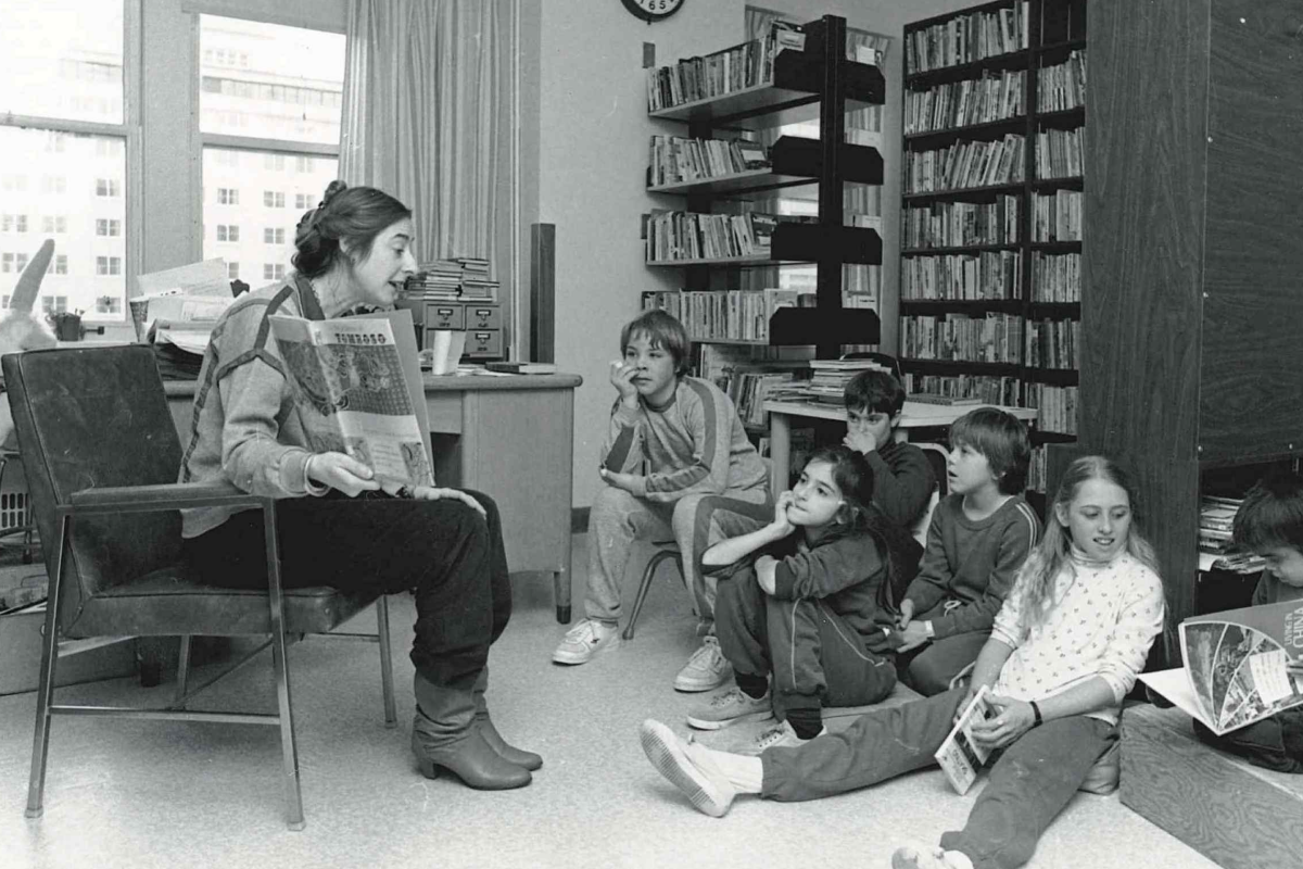 Historic SickKids hospital photo showing woman reading to young patients in the hospital library, demonstrating early commitment to supporting children's development through educational activities during medical care.