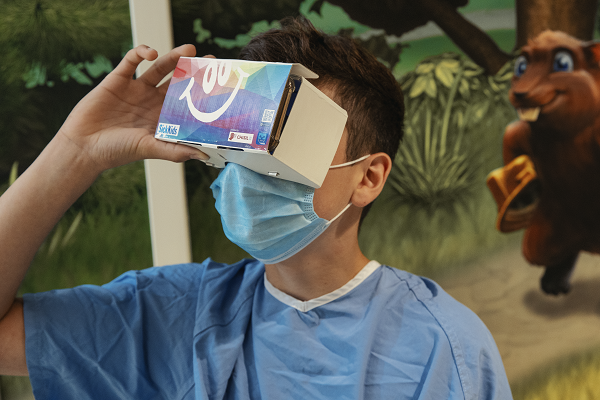 Teen looks into a cardboard VR set.