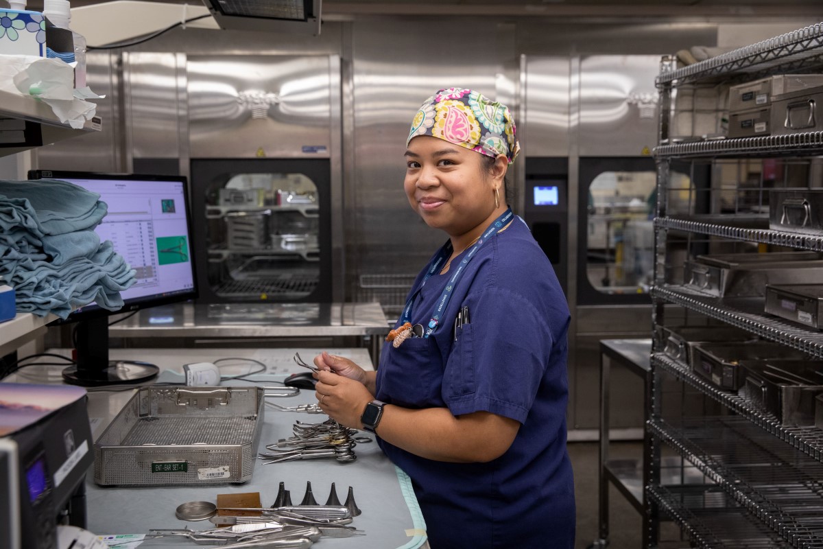 Woman stands at a workstation in an instrument cleaning facility.