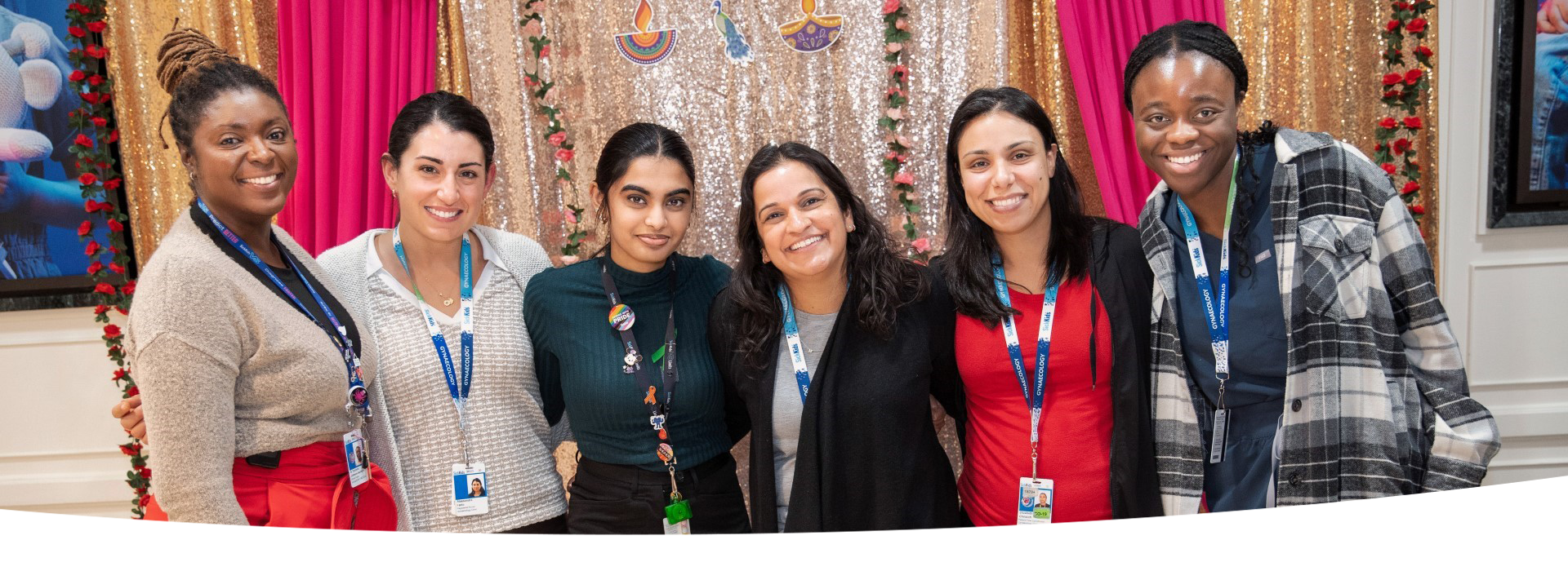 Group of staff stand together in front of a colourful background.