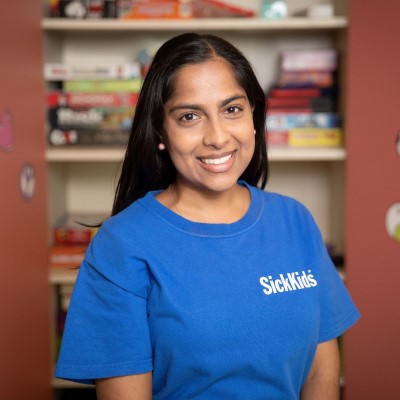 Volunteer stands in front of bookshelves filled with colourful books.