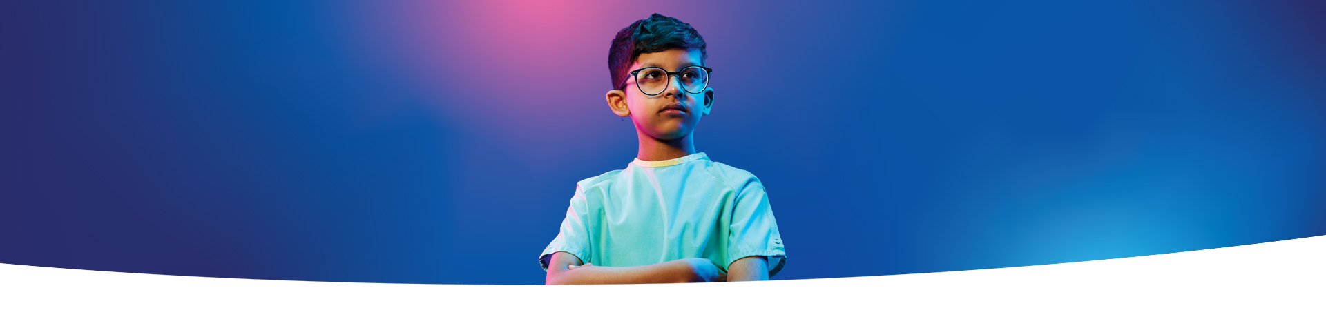 A boy wearing glasses and crossing his arms in front of a blue and pink gradient background.
