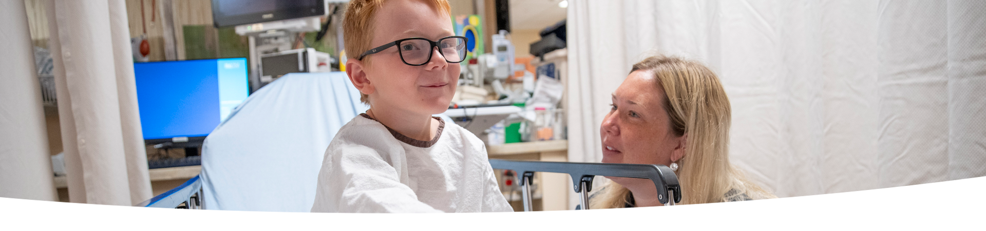 Child sits on a surgical bed, accompanied by an adult.