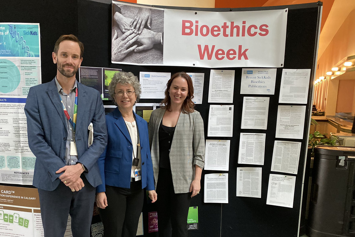 Three people stand together in front of an academic poster presentation.