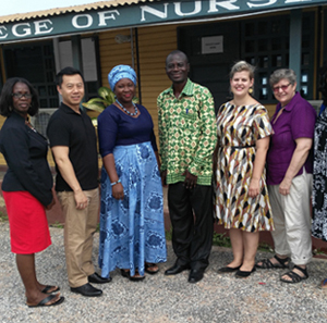 A group of five adults stand together outside a building that reads College of Nurses 