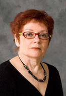 Headshot of a woman wearing red glasses and a black shirt.