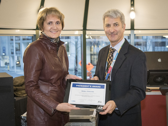 Woman and man stand side by side holding plaque.