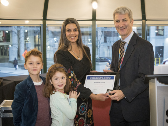Woman, two children and man pose together with a plaque.