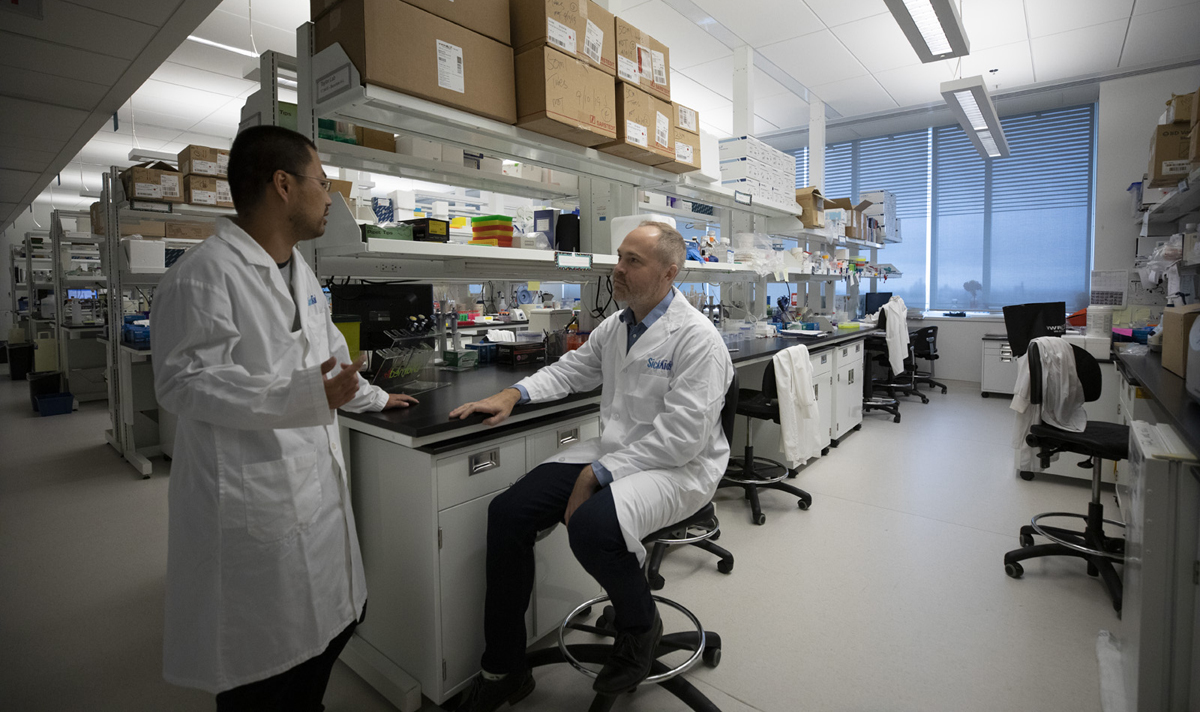 Michael Taylor and Hiro talk at a lab bench.
