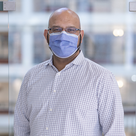 Headshot of Aamir Jeewa. He wears a mask and button down shirt.