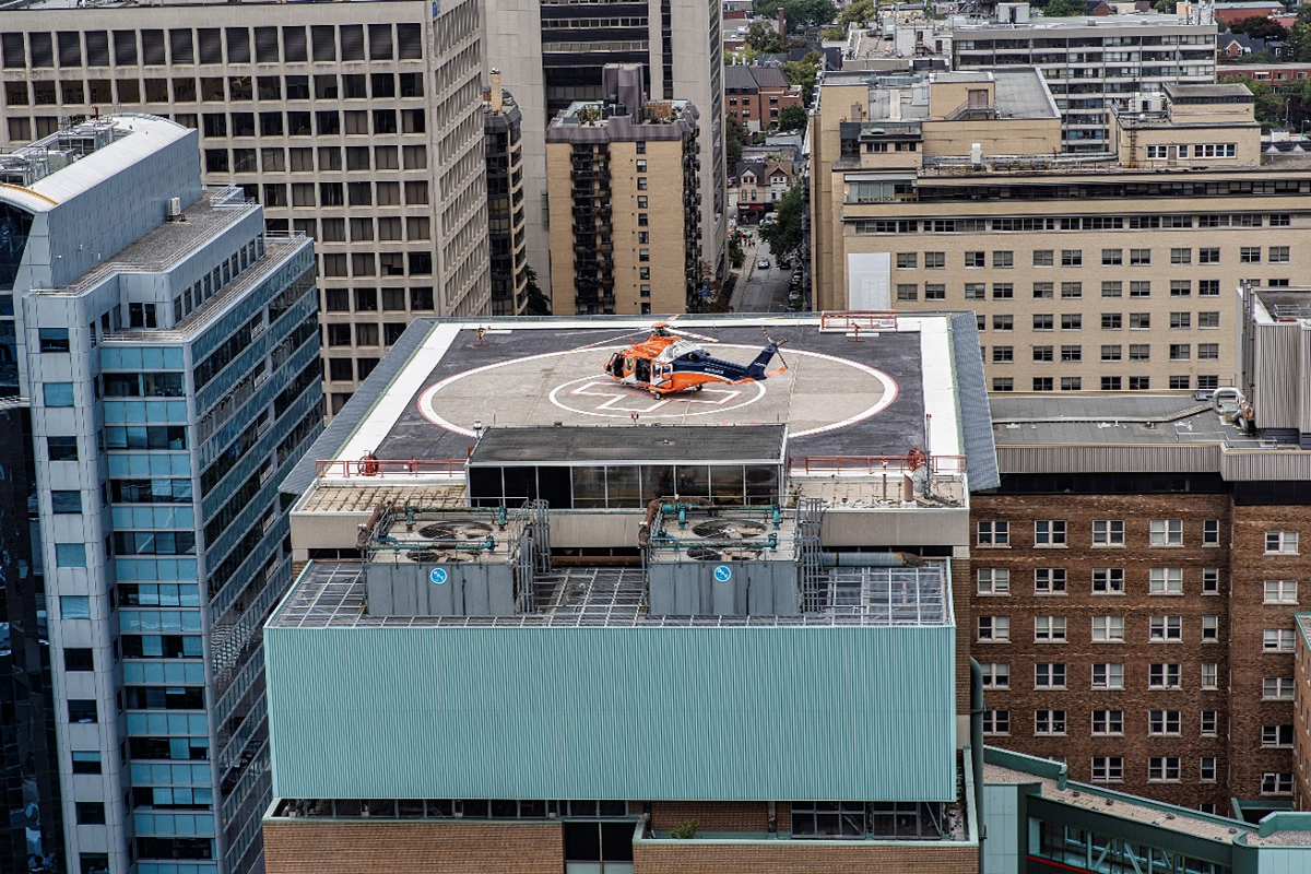 Orange helicopter lands on the roof of a building.