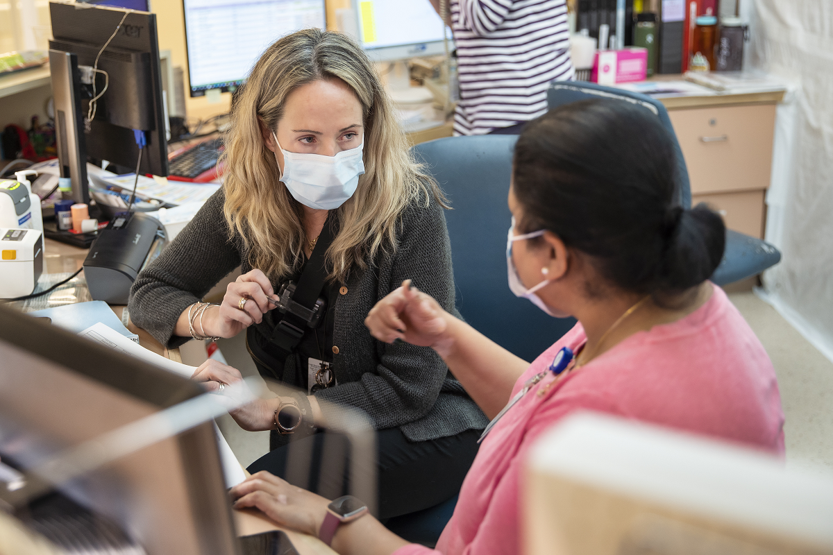 Two people in conversation, wearing masks.