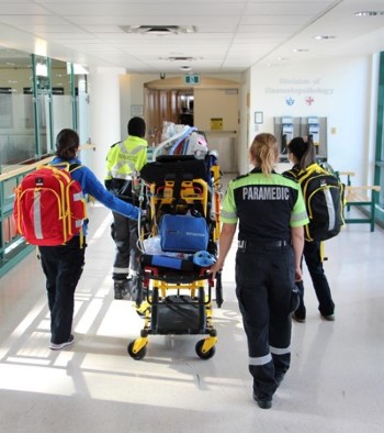 A team of paramedics and clinicians leading a stretcher down a hallway at SickKids