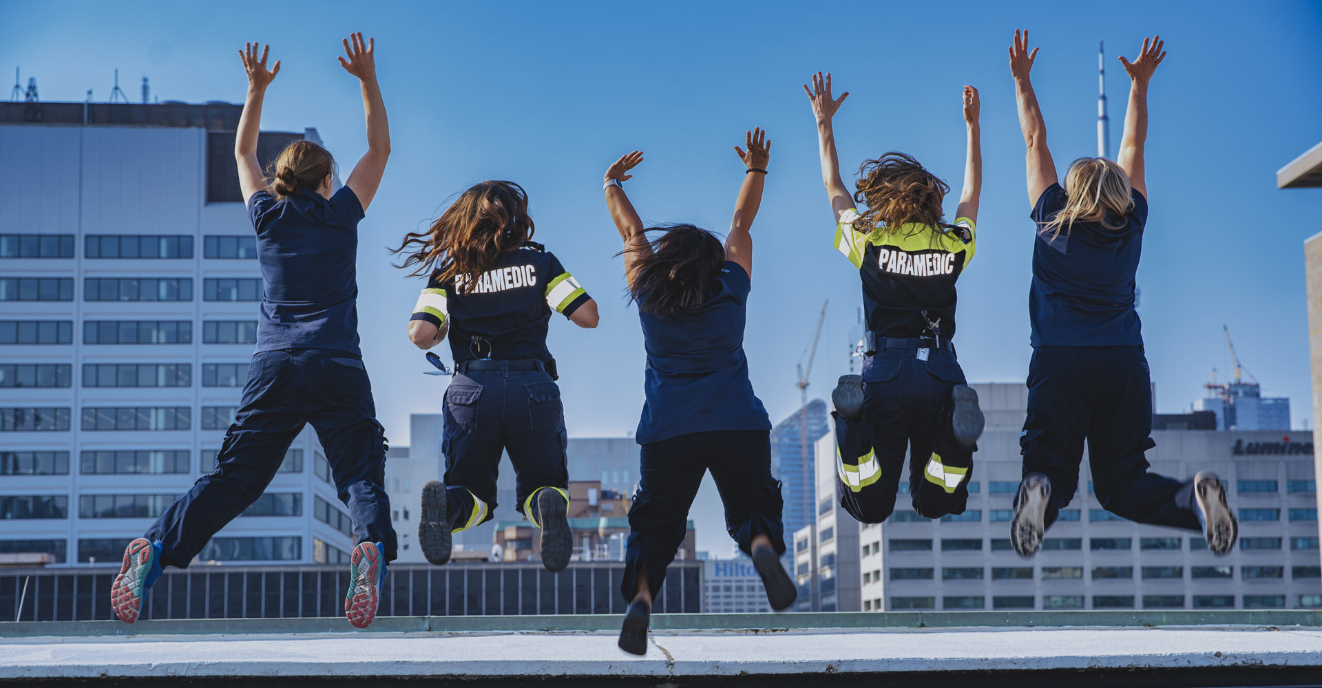 ACTS team members jumping in the air in unison on top of the SickKids helipad.