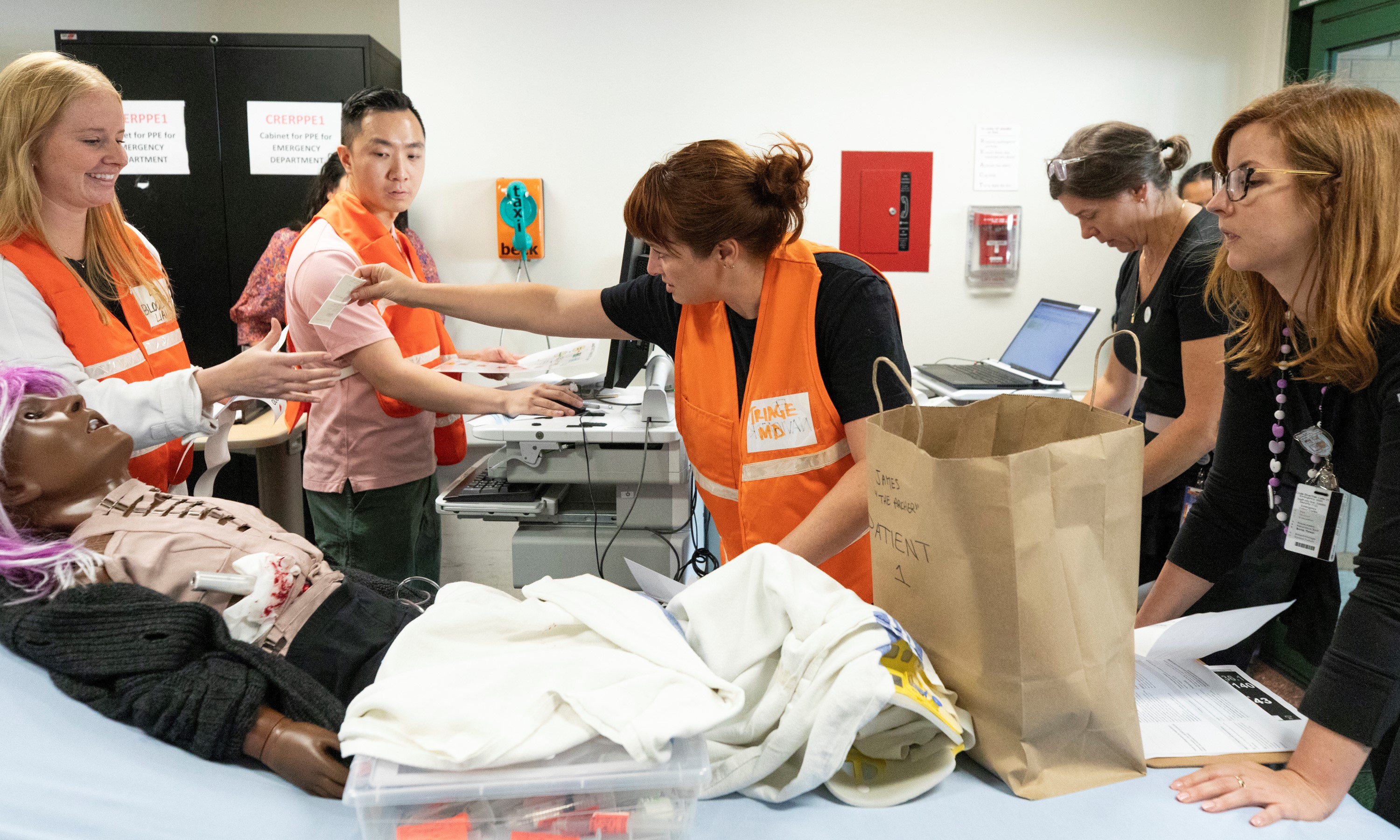 A simulated patient  arrives in the ambulance bay at SickKids as two nurses and an ED physician triage them.  