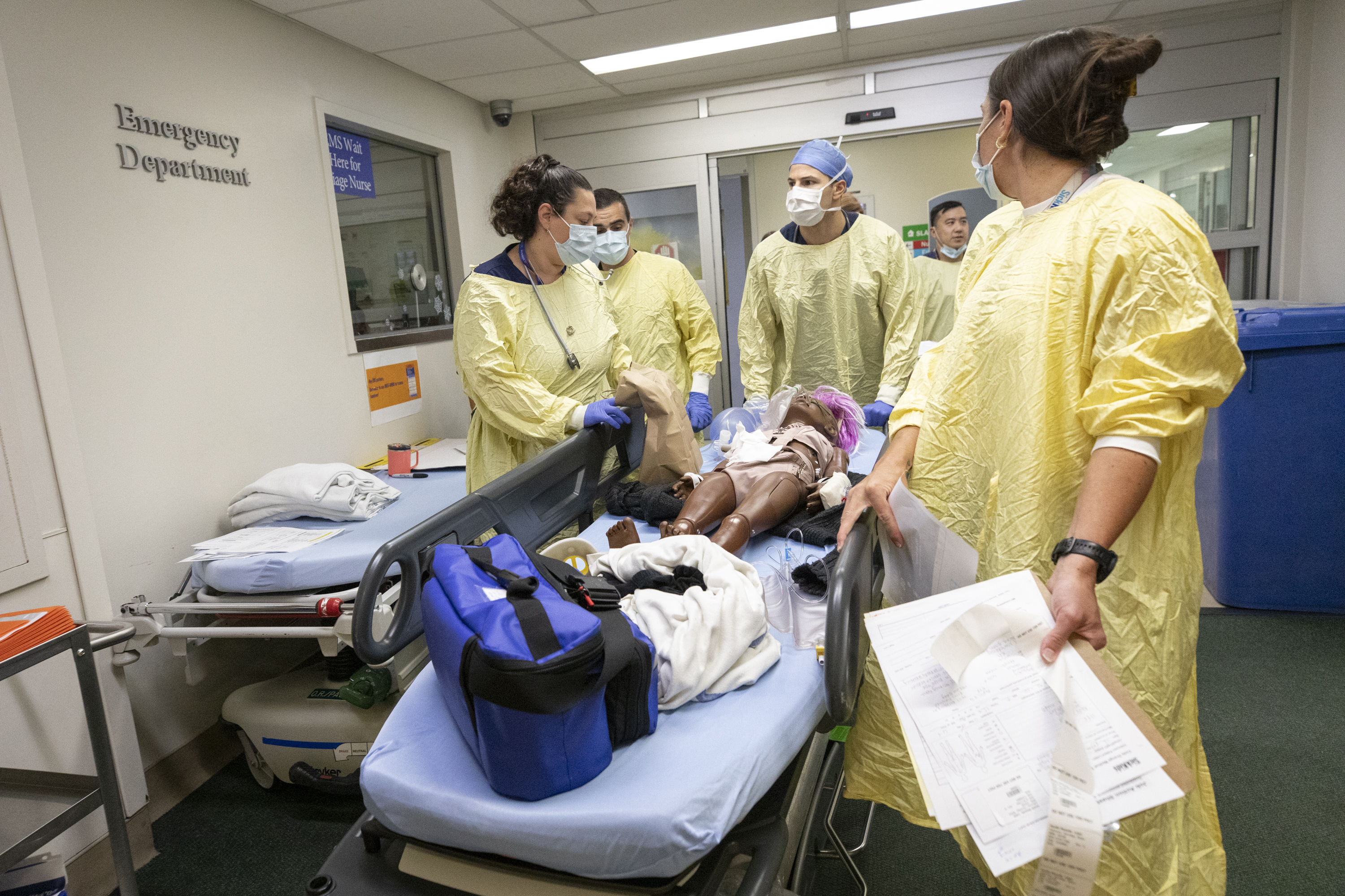 A full care team  transports a simulated patient carefully to surgery on the second floor.