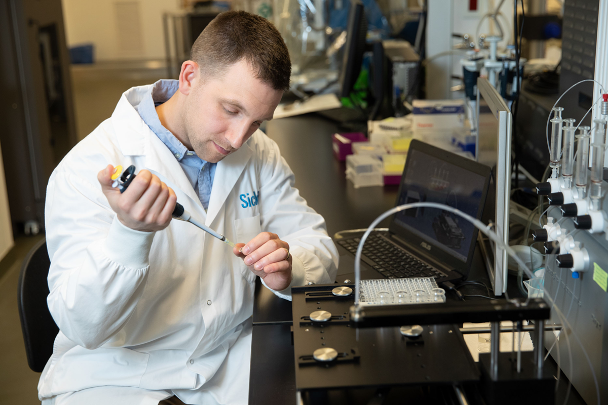 A scientist works at a lab bench looking down at his hands.