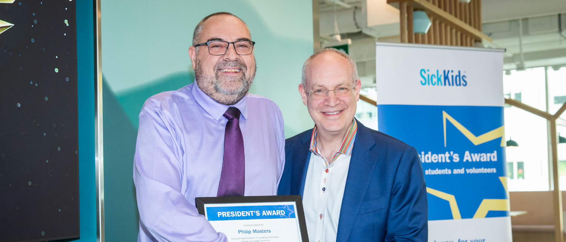 Philip Masters (left) smiling and holding his President's Award certificate posing for a photo with Dr. Ronald Cohn (right).