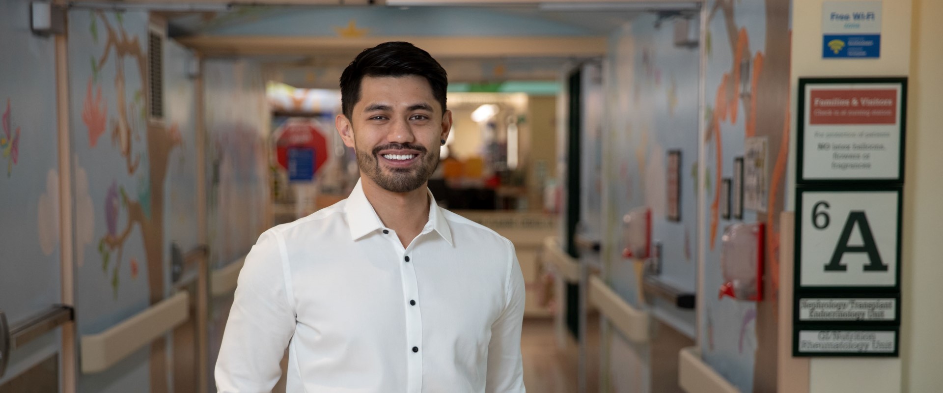 A person in a white dress shirt standing in a brightly lit hallway.