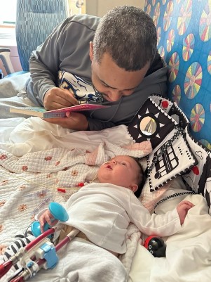 Sloane looks up at her dad Justin as he reads her a book.
