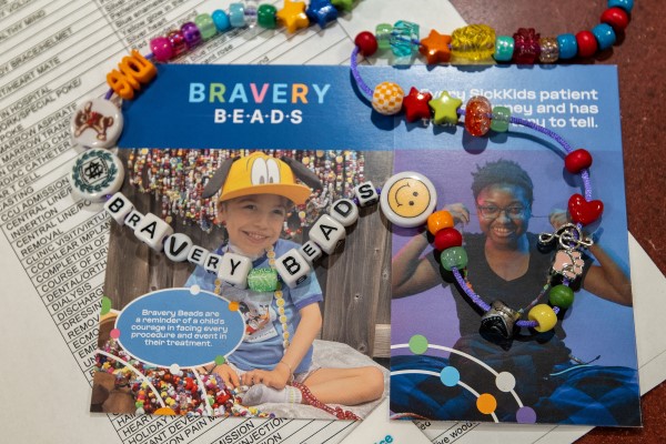 A string of beads, including bead letters that read "Bravery Beads," lie on top of an info card about the program. 