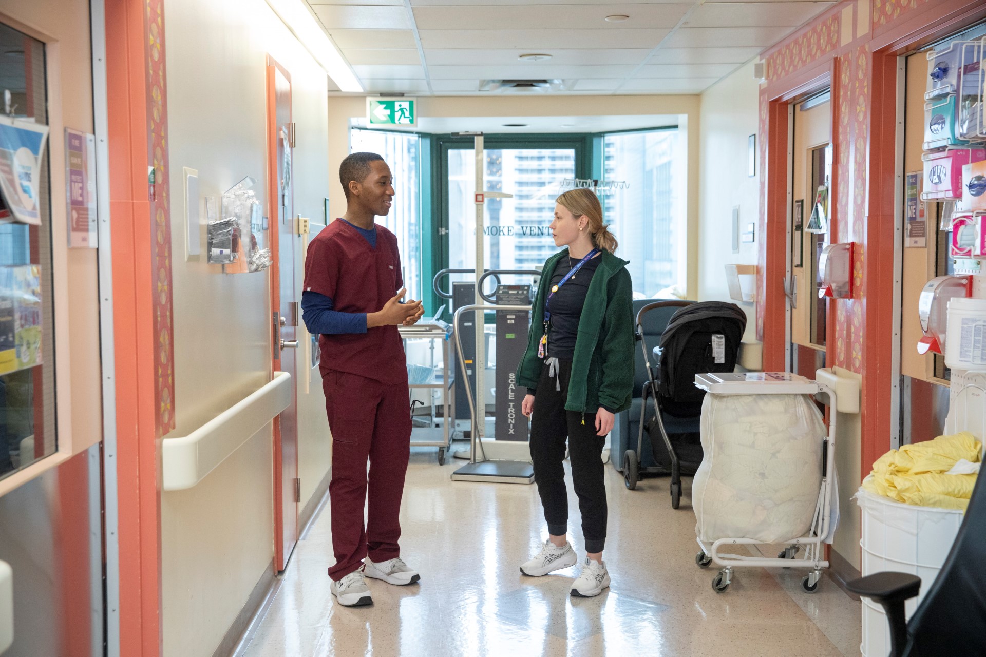 Standing in a hallway on 8B, James speaks to another nurse, Nina.